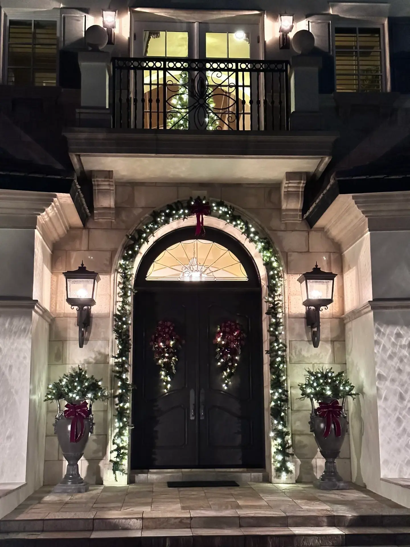 Grand front entry with lit garland, wreaths and red bows